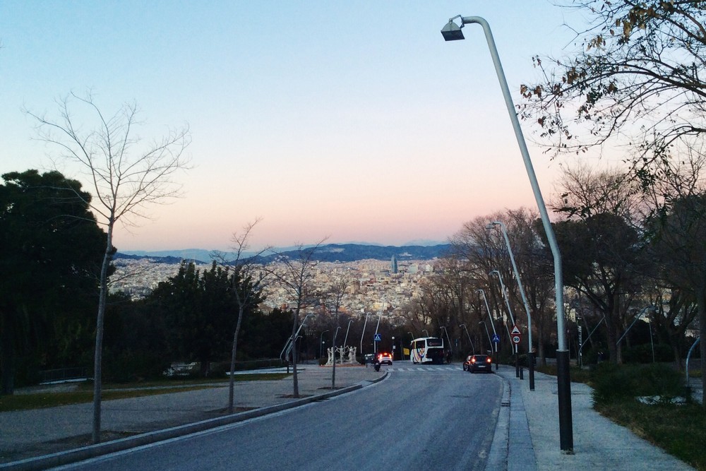 Walking up the hill, going on an empty road and looking back to the city - Barcelona, Spain
