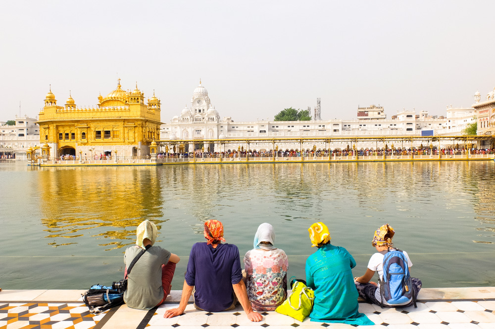 Tourists sitting and looking at The Golden Temple - Amritsar, India